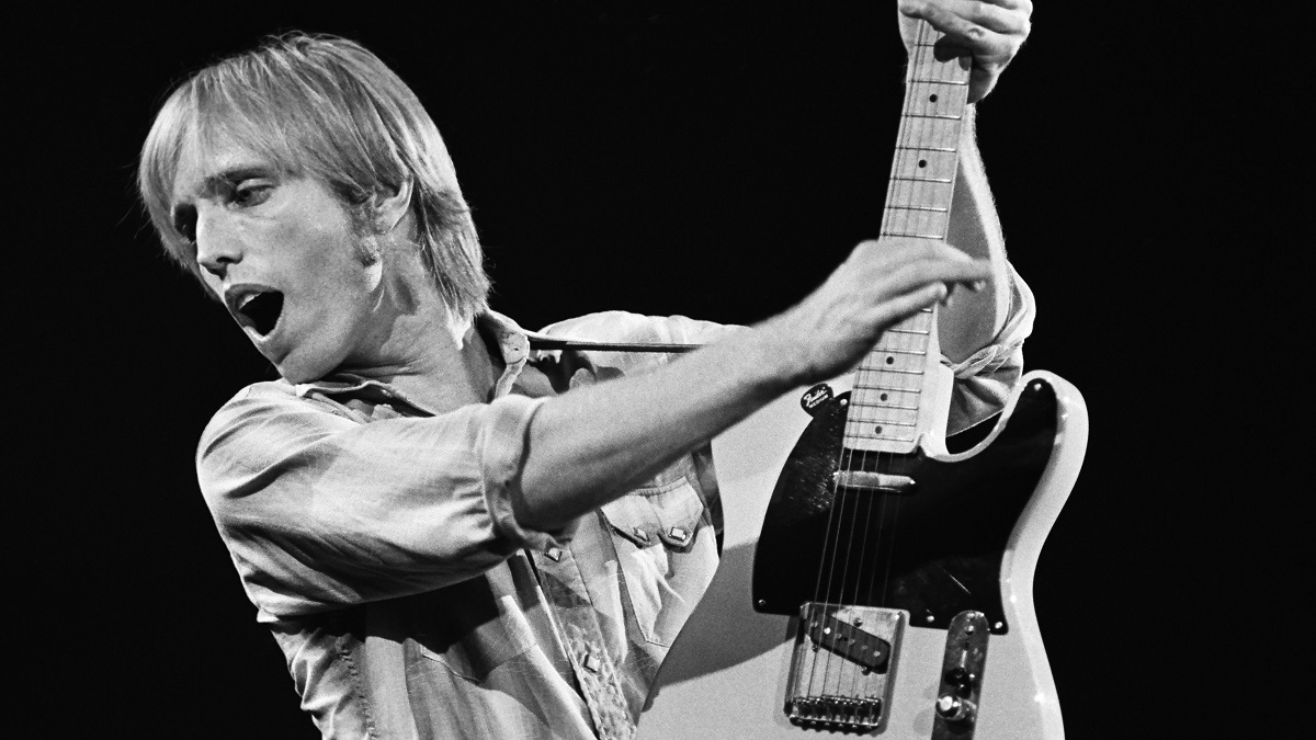 Black and white photo showing Tom Petty lifting his guitar up.