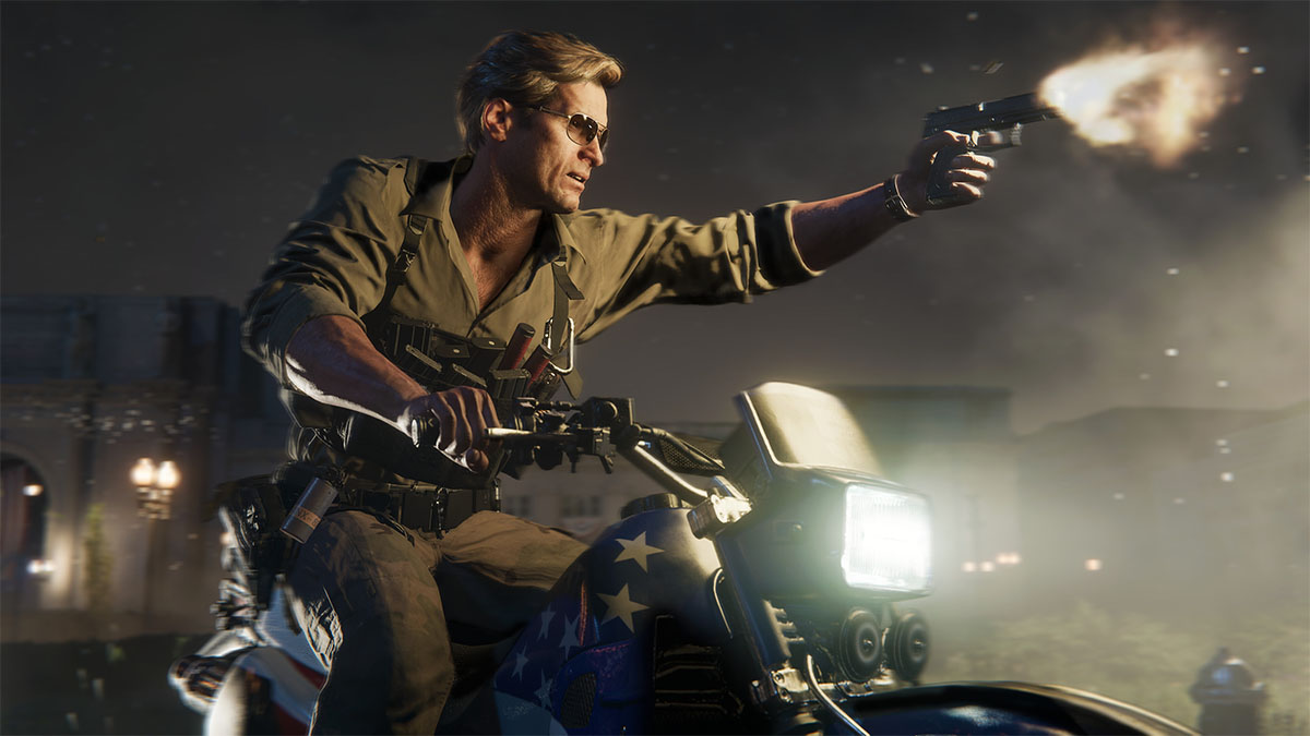 A man wearing sunglasses sitting an a motorbike, aiming a pistol in his left hand.