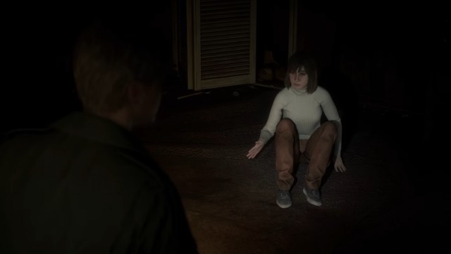 Silent Hill 2 remake: Angela cowering on the floor as James shines a flashlight on her.
