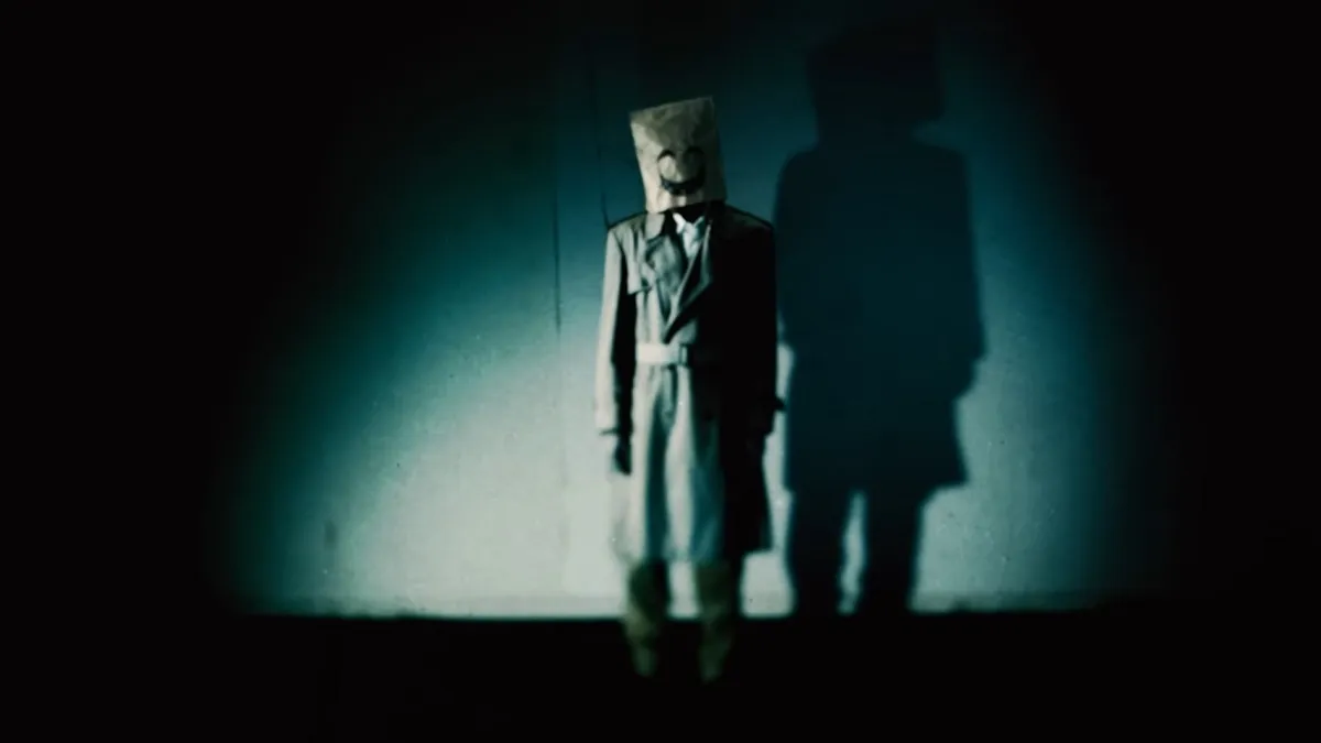 Still from a Nintendo video showing a creepy person in a trench coat and wearing a paper bag on their head.