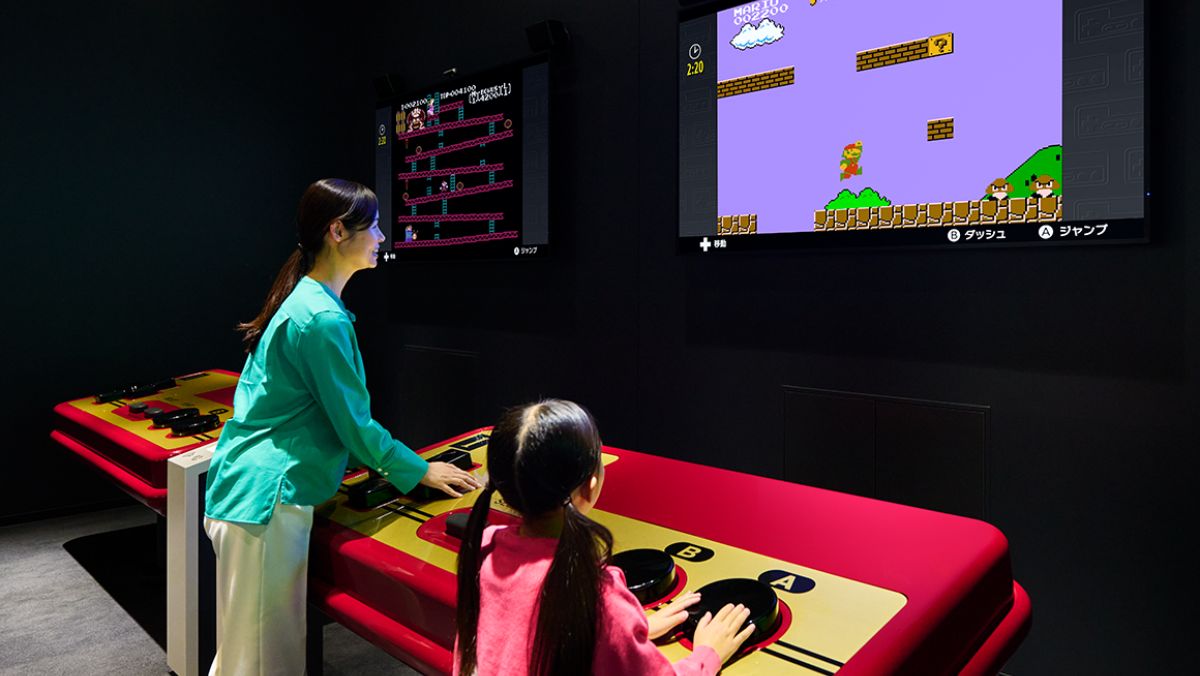 Two people using the giant NES controller at the Nintendo Museum.