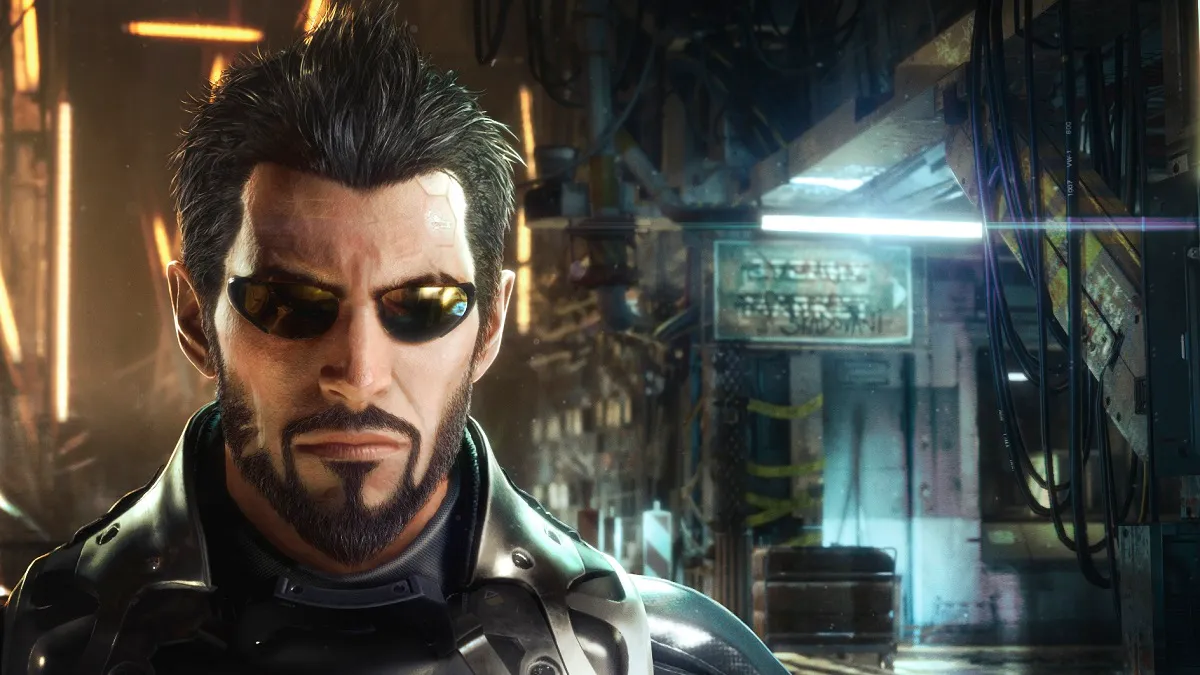 Deus Ex Mankind DIvided: Adam Jensen looks forlornly towards the camera, as a dystopian city looms in the background.